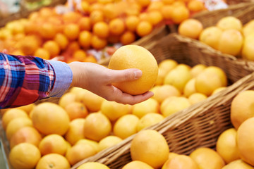 Hand with grapefruit in fruit supermarket