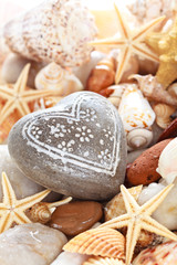Heart shaped pebble against seashells background .
