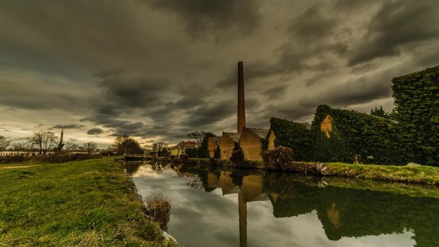 alte fabrik bei fluss mit regenwolken zeitraffer