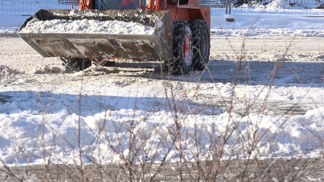 mini excavator work on street, cleaning snow in parking. Static closeup shot. 4K

