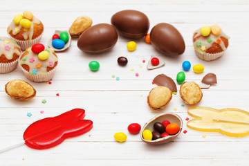 Chocolate Easter Eggs and Cupcake Over Wooden Background