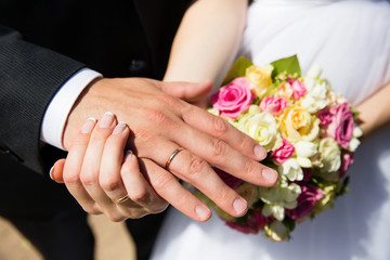 Obraz na płótnie Canvas Hands with wedding rings on bridal bouquet