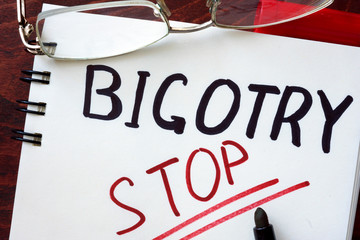 Stop Bigotry concept  written in a notebook on a wooden table.