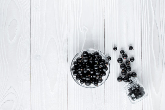 Black Currant In Glassware On White Wooden Table Top View