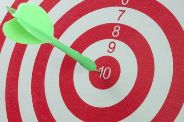 Green dart arrow hitting in the target center of dartboard
