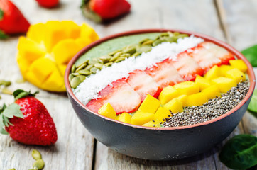 Spinach smoothie bowl with strawberries, coconut, mango, pumpkin