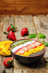 Spinach smoothie bowl with strawberries, coconut, mango, pumpkin