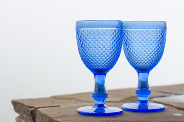Two glasses from blue glass on a foggy background