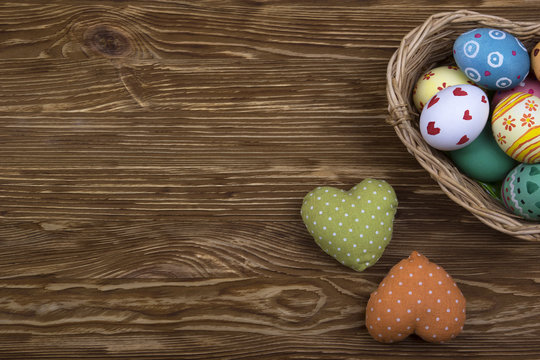 colorful easter eggs in a basket on wooden background