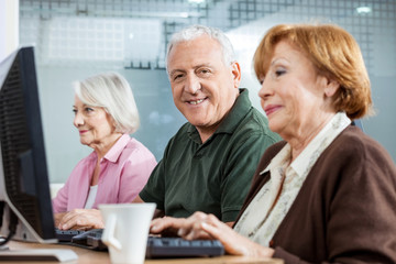 Confident Senior Man With Female Friends In Computer Class