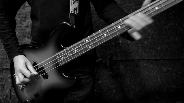 Musician playing electric bass guitar. Black and white.