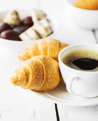 Hot cappuccino and pastries on white wooden boards