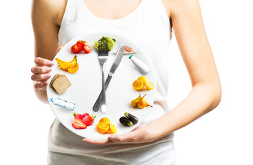 Beautiful young woman holding a plate with food, diet and time concept close up  - obrazy, fototapety, plakaty