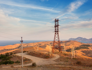 High voltage tower in mountains on the background of colorful sky at sunset.  Electricity pylon...