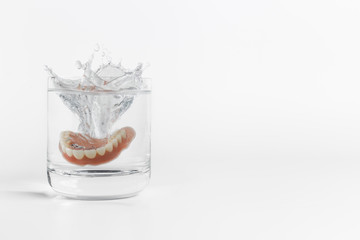 Dentures splashing in glass of water