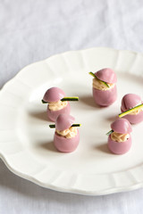 deviled quail eggs with cream cheese, dyed with beet juice.