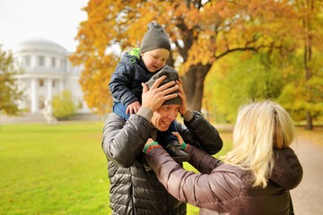 Fototapeta premium Wife corrects clothes for husband with child on a shoulders in park