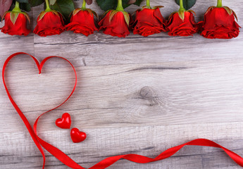 Heart made of red ribbon with red roses and pretty little hearts on a wooden board. Valentines day...