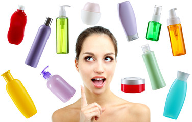 Beautiful young woman with gentle makeup and cosmetic bottles isolated on white