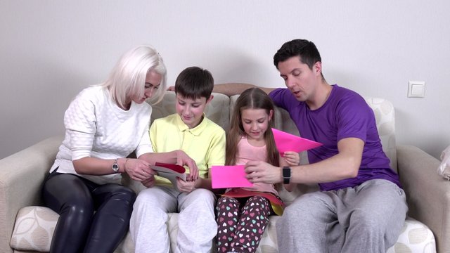 Happy big family makes from colored paper planes