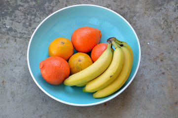 Bananas, valencia oranges and tangelos in large blue bowl