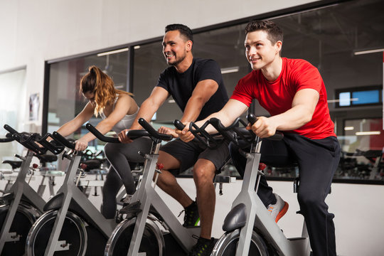 Male friends enjoying spinning in a gym