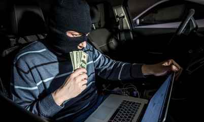 Hacker with a laptop inside a car