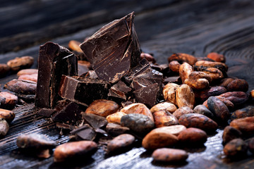 Chocolate pieces with cocoa beans on a wooden table