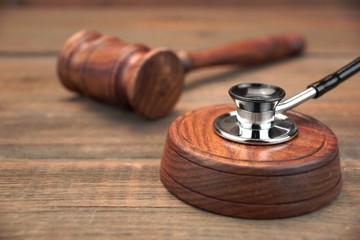 Stetoscope and Real Judges Gavel On Brown Wooden Background