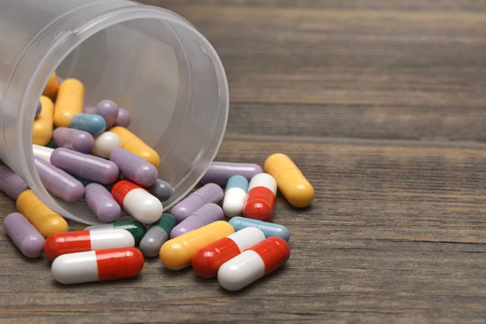 Many Colorful Pills And Capsules Dropped On Wooden Background