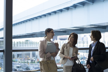 Three business women have a stand talking outside