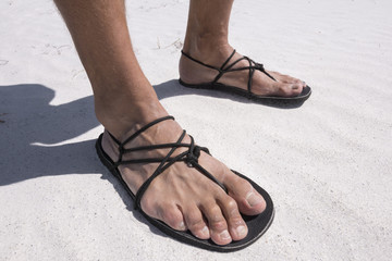Closeup primitive sandals worn on beach