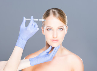 Doctor injecting botox in a beautiful face of a young woman. Plastic surgery concept.