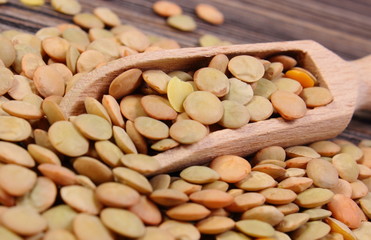 Heap of green lentil with spoon on wooden background