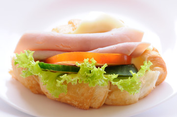 Croissant ham cheese on plate.