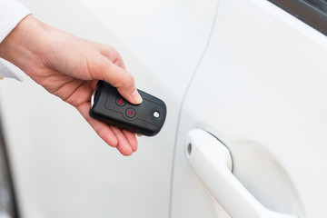 Female hand open the white car on key system automatic.