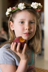 Portrait of girl with flowers in hair eating a peach