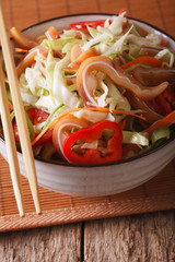 Asian cuisine: pork ears salad with fresh vegetables close-up. vertical
