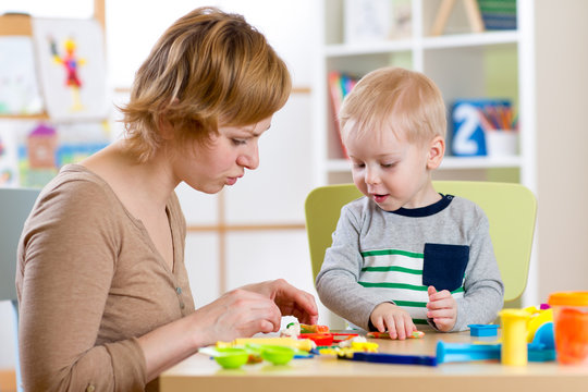 Child and woman play colorful clay toy in nursery