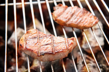 Grilled pork steaks over flames on the grill