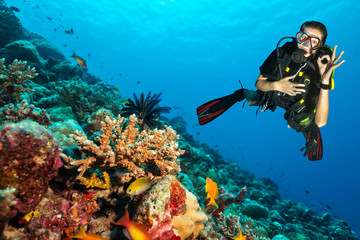 Un plongeur sous-marin explore un récif de corail montrant un signe ok