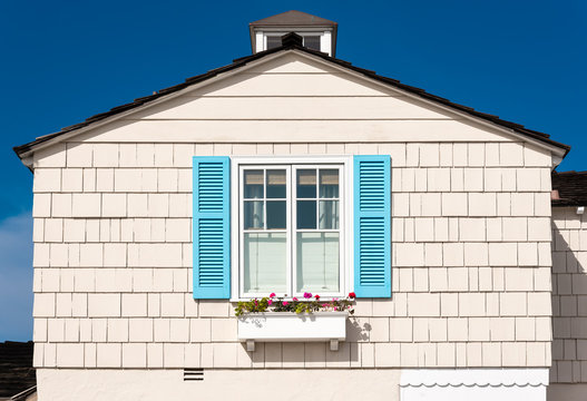 white wooden facade with blue shutters and flowers - Powered by Adobe