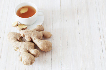 Ginger tea in a white cup on wooden background