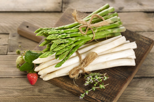 Eine Portion erntefrischer grüner und weißer Stangenspargel auf einem Holzbrett