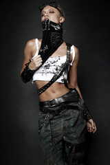 Young woman in brutal style clothes with goggles on studio black background