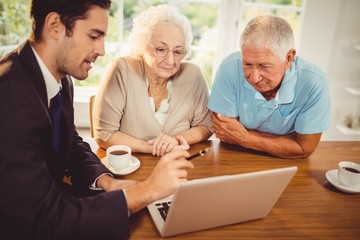 Businessman showing laptop to senior couple