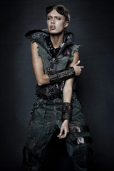 Young woman in brutal style clothes with goggles on studio black background