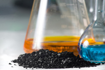 loose coal near the glass test tubes with colored liquid on grey