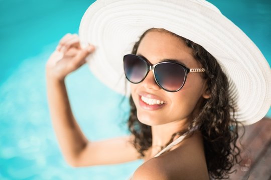 Beautiful woman in sunglasses sitting by pool
