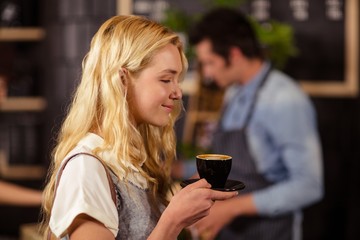 Portrait of smiling pretty customer smelling cup of coffee 